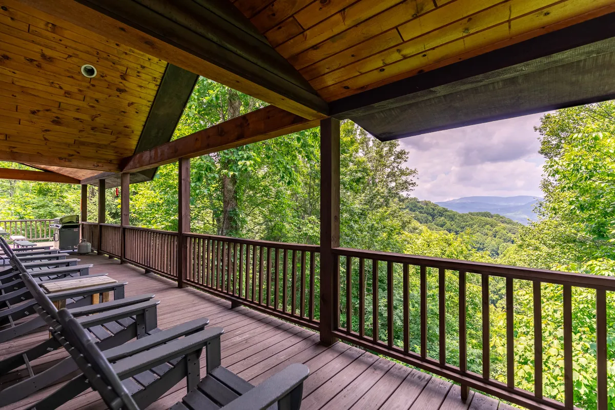 The image focuses on a wooden deck furnished with comfortable seating, all oriented to maximize sweeping mountain views. The expansive vista and serene atmosphere evoke the sensation of enjoying morning coffee or evening relaxation in the open air.